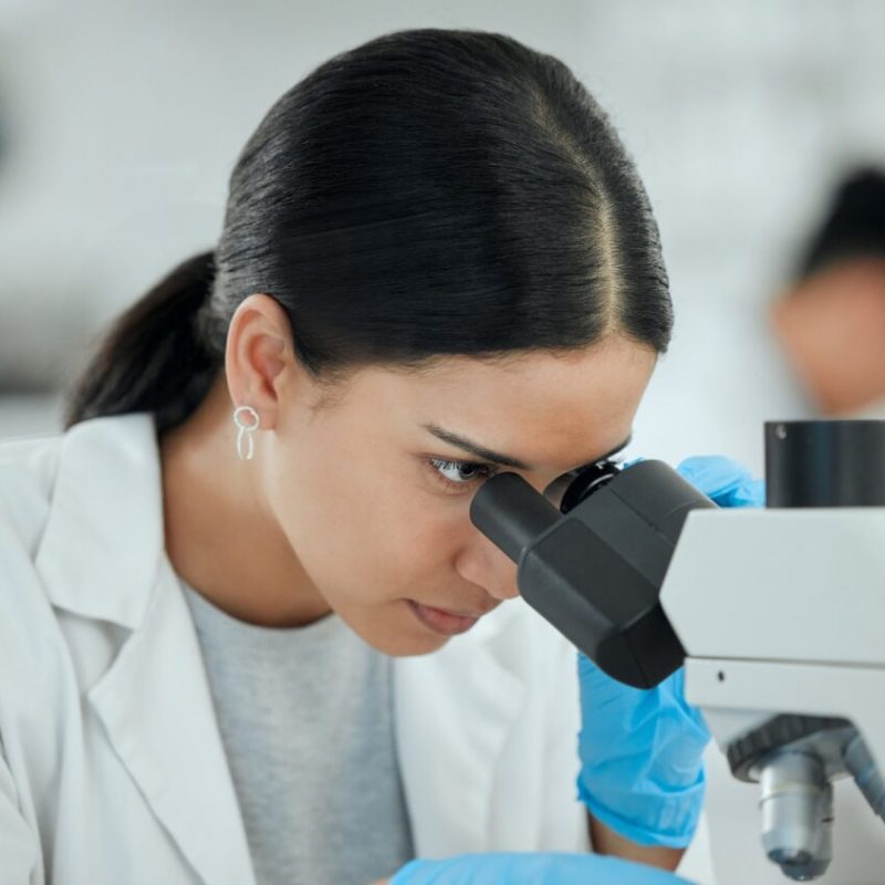 Worked my entire life to get here. Shot of a young woman using a microscope in a scientific lab.